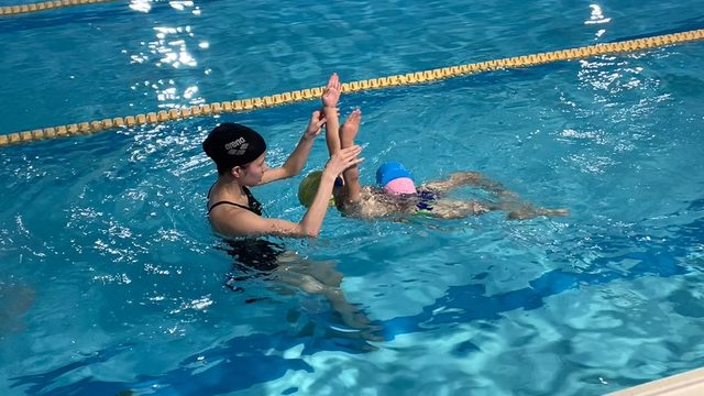 コーチが幼児に付き添うスイミングレッスン